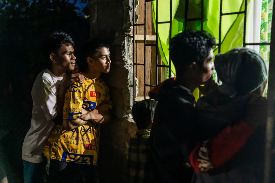 Curious onlookers gather to listen as a church service extends into the evening.